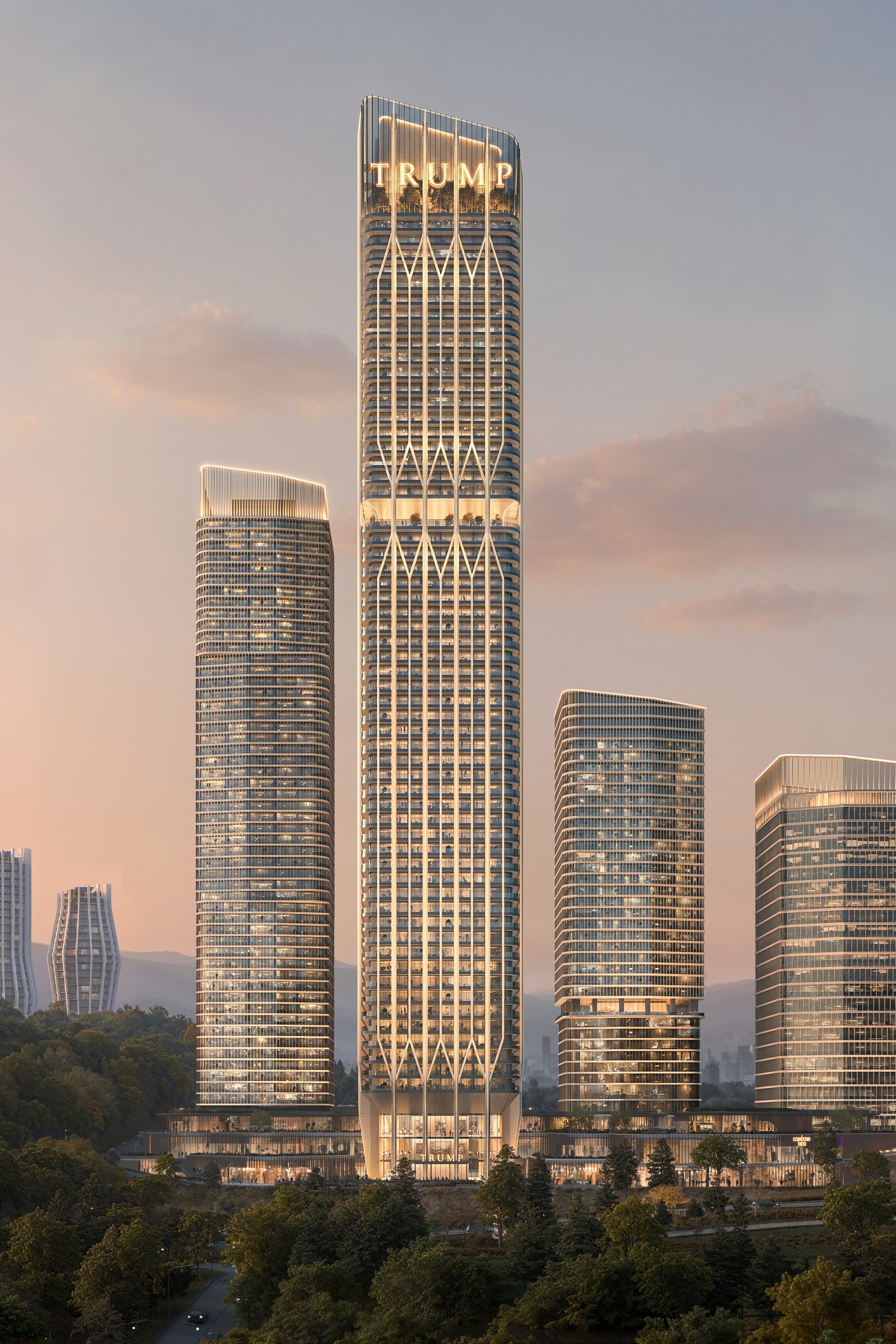 Trump Tower Tbilisi at dusk across the Central Park, its lit crown carrying the Trump name in gold, its full 62-floor height rising above the neighbouring towers of Downtown Tbilisi.