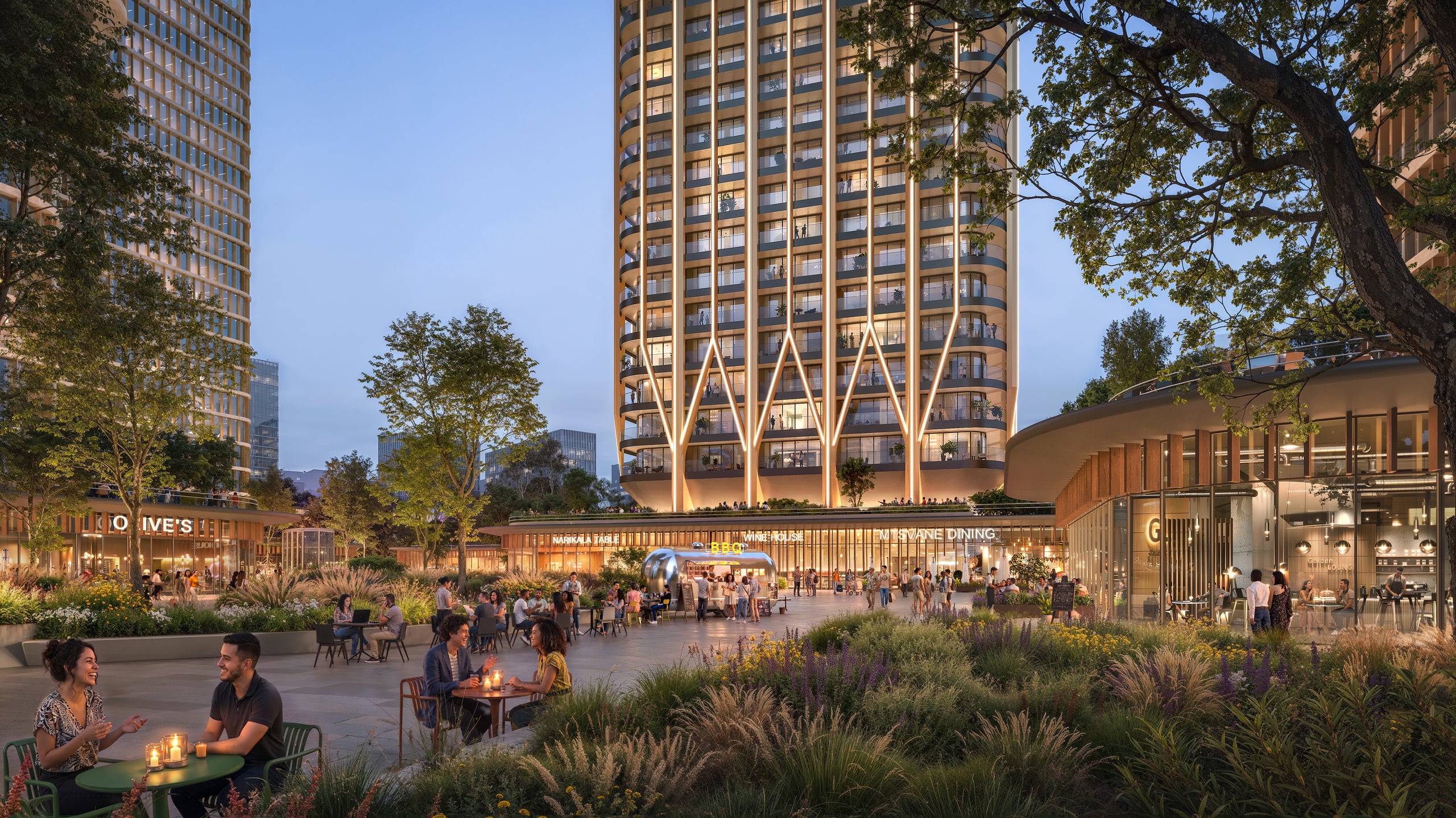 The plaza at dusk, with open-air dining and a street-food market below the lit tower.